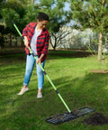 Person using Lawn Leveling Rake 30x10 Stainless Steel With 78 Inch Adjustable Handle Green Positioning Stakes Heavy Duty Leveler for backyard