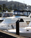Boats docked in a marina with trees and hills in the background, featuring white and blue watercraft with cabin enclosures.