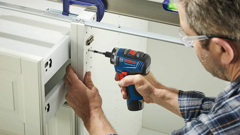 Man using 12V Max Brushless 1 Quarter Inch Hex Two Speed Screwdriver Kit With Dual 2.0Ah Batteries for DIY cabinet assembly