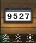 Solar Powered Address Sign With Bright LED House Numbers, Outdoor Waterproof Plaque For Exterior Walls, No Fuss Nighttime Visibility, Weatherproof Gray on wooden wall in rain