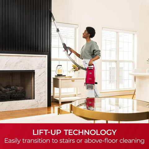 Person using Hassle Free Bagged Upright Vacuum With No Touch Auto Dump And Smooth Lift Up Pod For Stairs for above-floor cleaning.