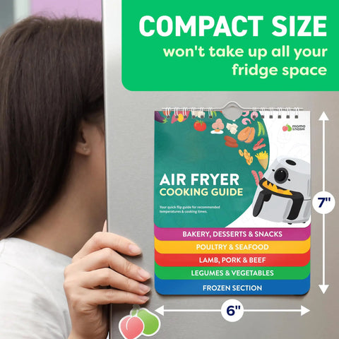Person holding 7x6 inch Air Fryer Cheat Sheet Magnet And Quick Reference Guide With 120 Plus Foods across five categories on fridge.