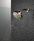 H2Okinetic 5 Setting Raincan Shower Head in Champagne Bronze with touch clean spray holes and water stream on dark tiled wall.