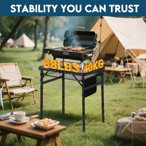 Small Folding Grill Table For Camping And Outdoor Cooking Portable BBQ Ready Picnic Stand With Three Height Settings 10.7 Inch, 19.5 Inch, And 27.7 Inch Holds Grill, Food And Tools Heavy Duty Up To 88 Lb Capacity Includes Mesh Storage Bag Black in campsite with grill and food.