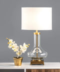 Hendry 23 Inch Glass Table Lamp With Brass Finish, Fabric Drum Shade, next to a potted orchid on a modern table