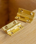 100 Pcs Mini Brass Hinges For Cabinets And DIY Projects, Gold Finish Small Butt Hinges 0.4 By 0.3 Inch, on a wooden surface