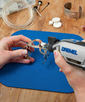 Close-up of hands using Dremel tool on metal pieces with Nitty Gritty 20 Piece Rotary Tool Accessory Cleaning Kit.