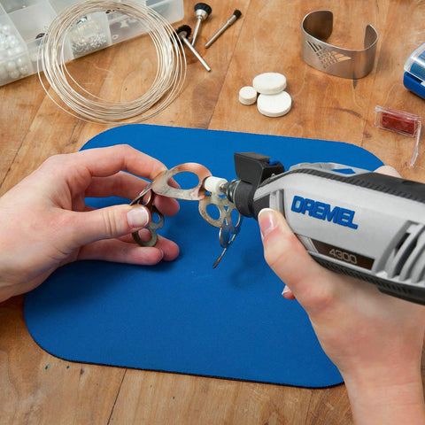 Close-up of hands using Dremel tool on metal pieces with Nitty Gritty 20 Piece Rotary Tool Accessory Cleaning Kit.