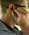 Man adjusting Behind The Neck Bluetooth Hearing Enhancer For Hunters With Retractable Earbuds, worn around neck