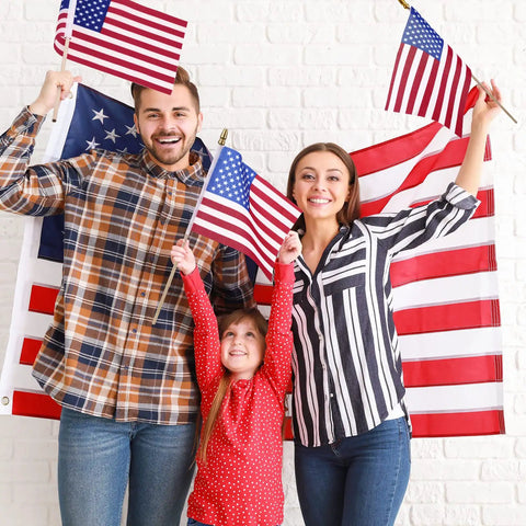 Family holding 50 Pack 8x12 Inch American Flags On Sticks With Solid Wooden Poles And Safety Spear Tips Great For 4th Of July Parades