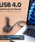 Straight Fire USB4 40Gbps M.2 NVMe SSD Enclosure Docking Station on wooden table connected to laptop, featuring USB 4.0 interface.