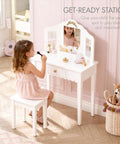 A girl using a Kids Vanity Table Set With Gold Bow for Little Girls in a playroom, featuring a white wood makeup desk and mirrors.