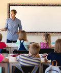 Teacher in classroom with students, Colorful Confetti On Black Border Trim Roll 50 Foot To Liven Up Classroom Decor visible on board.