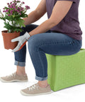 Person using green Built Tough 3 Level Work And Garden Seat With Flip Heights At 9, 12 And 15 Inches, One Piece Weatherproof Construction For Indoor And Outdoor Use, Made In USA while gardening.
