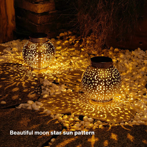 Outdoor Solar Lanterns 2 Pack Waterproof Hanging LED Lights With Metal Star Moon Sun Pattern illuminating a dark garden path.