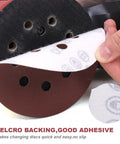 Peeling 5-inch sanding disc with velcro backing, showing 8-hole design. 200-Piece 5-Inch Sanding Discs Set With 8-Hole Hook And Loop Orbital Sandpaper Assorted Grit Pack Includes 40 60 80 100 120 150 180 240 320 400 600 800 1000 Grits For Woodwork And Metal Finishing Great For DIYers