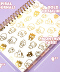 Hello Kitty Pink Gold Foil Journal Set For Girls with spiral binding, gold detailing, monthly tabs on purple background.