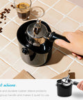 Hand holding a portafilter over Grindenstein Espresso Knock Box Sturdy and Compact Black Coffee Grounds Container, modern design
