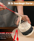 Complete Sourdough Starter Jar Kit 35 Oz Large Glass Jar with red silicone spatula stirring dough in marked jar