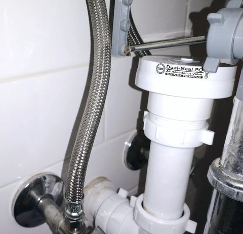 Air Admittance Valve and 1-1/2 Inch P-Trap Kit for Sink Drain, installed under a sink, white tubular venting system