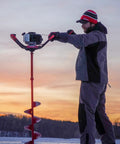 Person using 12 Inch Ice Auger Extension for Powerheads with 7/8 Inch Connection at sunrise, showing auger and extension in use.