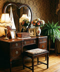 Antique wooden dresser with ornate mirror, floral arrangement, and vintage decor in elegant room with patterned wallpaper and curtain.