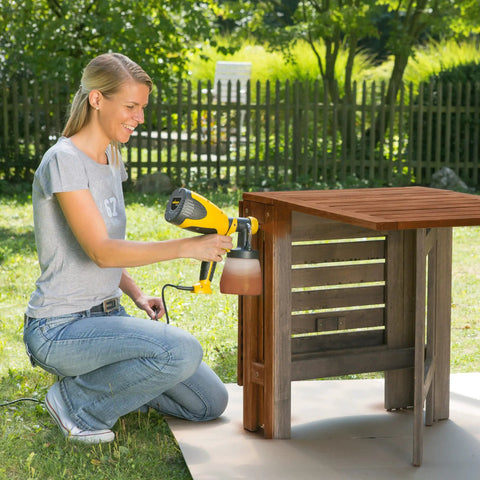 Person using Control Spray Max HVLP Paint and Stain Sprayer With Fully Adjustable Settings For Decks Cabinets Furniture And Woodworking Includes Extra Container In Bright Yellow And Black For A Smooth Finish On Thin Materials on outdoor furniture