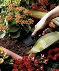 Hand using a trowel from a Lightweight Garden Hand Tools Set With Trowel Transplanter And Cultivator Fiber Composite Nylon Fiberglass