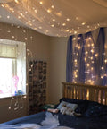 Bedroom with 300 LED Curtain String Lights With 8 Modes For Weddings And Parties Warm White Fairy Twinkle For Window Decor Home Garden Indoor And Outdoor Wall Hangings installed on ceiling and wall, soft glow lighting the room.