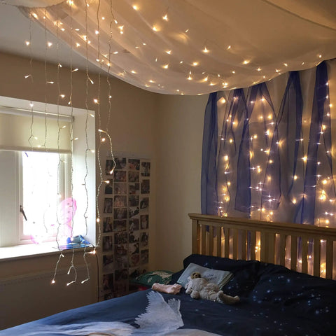 Bedroom with 300 LED Curtain String Lights With 8 Modes For Weddings And Parties Warm White Fairy Twinkle For Window Decor Home Garden Indoor And Outdoor Wall Hangings installed on ceiling and wall, soft glow lighting the room.