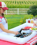 Person using Three-Piece Inflatable Serving Bars Set With Drain Plug And Pump, Ice Cold Bar For Food And Drinks at outdoor picnic.