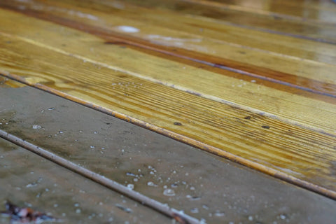 Image of wooden deck boards showing remnants of old stain and water spots after using One Gallon Ready To Roll Deck Stain Stripper.