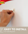 Installing a Quartz Plastic Spring Clip from 8 Pack for Dorm Décor, easy to mount without tools, shown on a white wall.