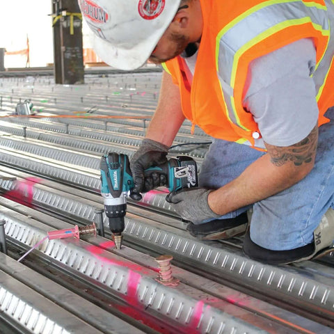 Worker using Rock Solid Eighteen Volt Cordless Hammer Driver Drill Kit Featuring Killer Torque Two Speed Gears on metal beams.