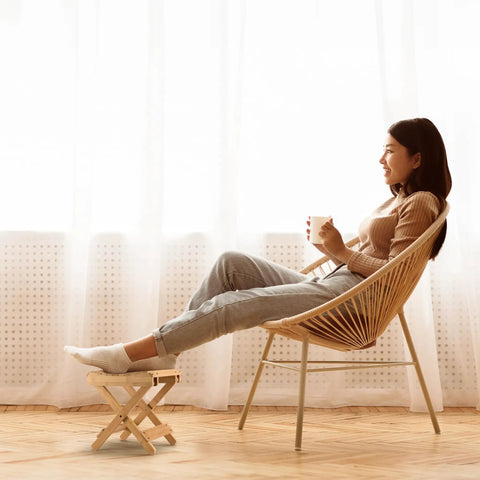 Woman relaxing with a Foldable Shower Stool For Tiny Bathrooms Bamboo Foot Rest And Shaving Stool Space Saver Portable Folding Shower Bench