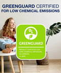 GreenGuard certified logo for low chemical emissions next to a relaxed woman on a sofa with a plant and table nearby.