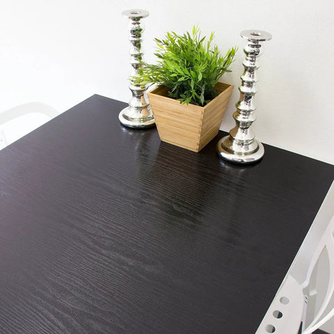 Table surface covered with Blackwood Peel And Stick Self-Adhesive Decor Film 17x78 Inch Roll 4-Pack Wood Grain Vinyl Wrap For Walls Cabinets Furniture And Shelves Easy DIY Makeover That Looks High End, featuring ebony wood grain design, with a plant and candlesticks on top.