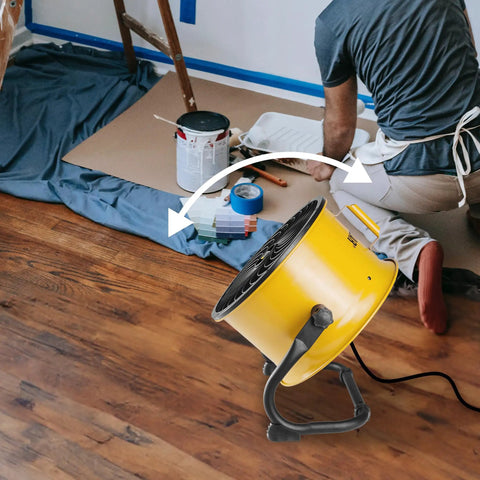 Industrial Grade 14 Inch High Velocity Drum Fan With Four Speed Settings in use on jobsite, yellow fan on floor, worker painting