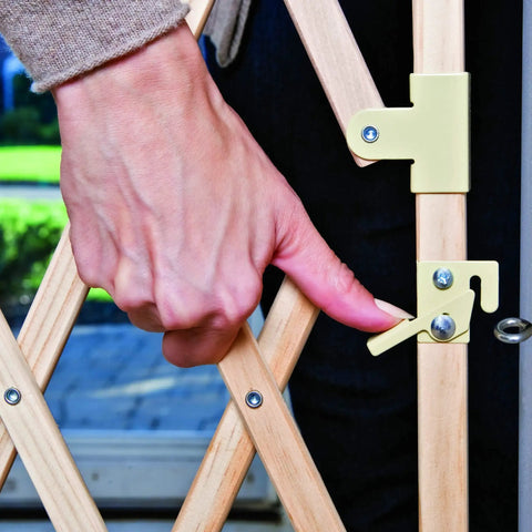 Close-up of hand using latch on Expansion Walk Thru Room Divider Baby Gate In Natural Wood Fits Openings From 24 To 60 Inches Wide