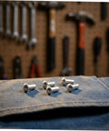 Five Two Hundred Aluminum Brazier Head Rivets M5x10 Millimeters With A Sleek Silver Dome Shape on denim fabric.