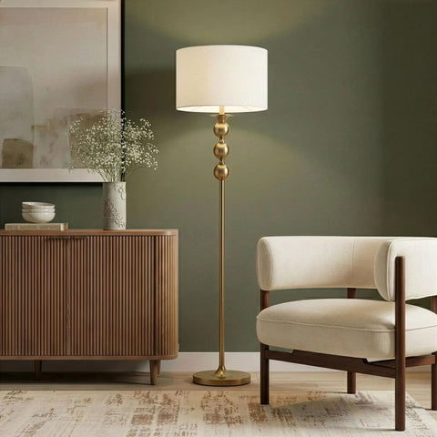 Riley 60 Inch Floor Lamp With Drum Shade In Gold Brass Finish For Living Room Or Bedroom Modern Standing Lamp With Boho Chic Mid Century Vibe And Elegant Corner Light For Office, shown in a living room setting.