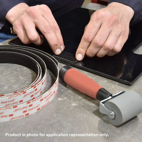 Hands applying Clear Low Profile Reclosable Fastener Roll Crafted From Tough Polyolefin Tape With Interlocking Mushroom Heads on a surface.