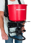 Person demonstrating Pro Grade Chest Mount Hand Crank Spreader with Even Spread Technology 40 lb Hopper and adjustable harness.