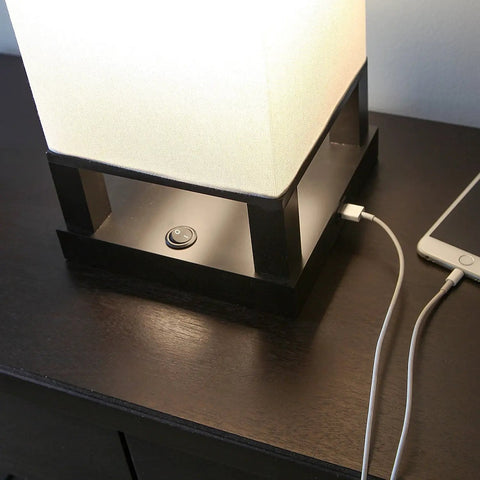 Maxwell Bedside Lamp With USB Port for Bedroom, showing wood frame base with built-in USB charger and soft LED glow beside phone