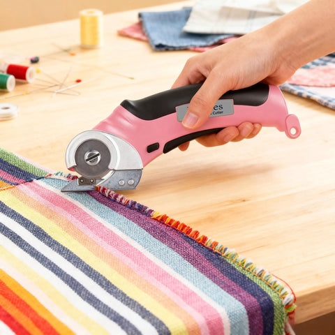 Heavy Duty Cordless Electric Scissors With Fast Usb Rechargeable Power And Self Sharpening Steel Blades For Slick Cuts Through Denim Fabric Leather Carpet And Stubborn Cardboard In Nifty Pink cutting striped fabric on a wooden table.