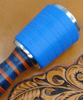 Close-up of Professional Leather Tooling Maul with blue nylon head and striped leather handle on embossed leather background.