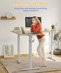 Woman using Game Changer L Shaped Standing Desk With Electric Height Adjustment, 63 By 55 Inch Reversible Corner Workspace, Natural Finish, home office.