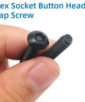 Close-up of black Hex Socket Button Head Cap Screw held in fingers from All In One M5 Screws and Nuts Kit With 240 Pieces Including M5x6mm 8mm 10mm 12mm 16mm 20mm 25mm 30mm Hex Button Head Socket Cap Screws 80 Nuts 80 Washers Wrench Black Zinc Plated