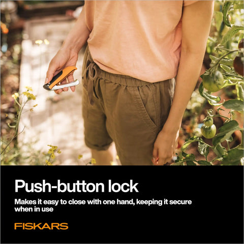 Person holding Foldable Produce Knife For Garden Harvests with one-handed safety lock in a garden setting.