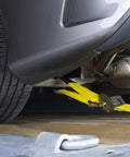 Two Inch Wide By Thirty Six Inch Long Premium Axle Tie Down Strap With D Rings securing vehicle on trailer
